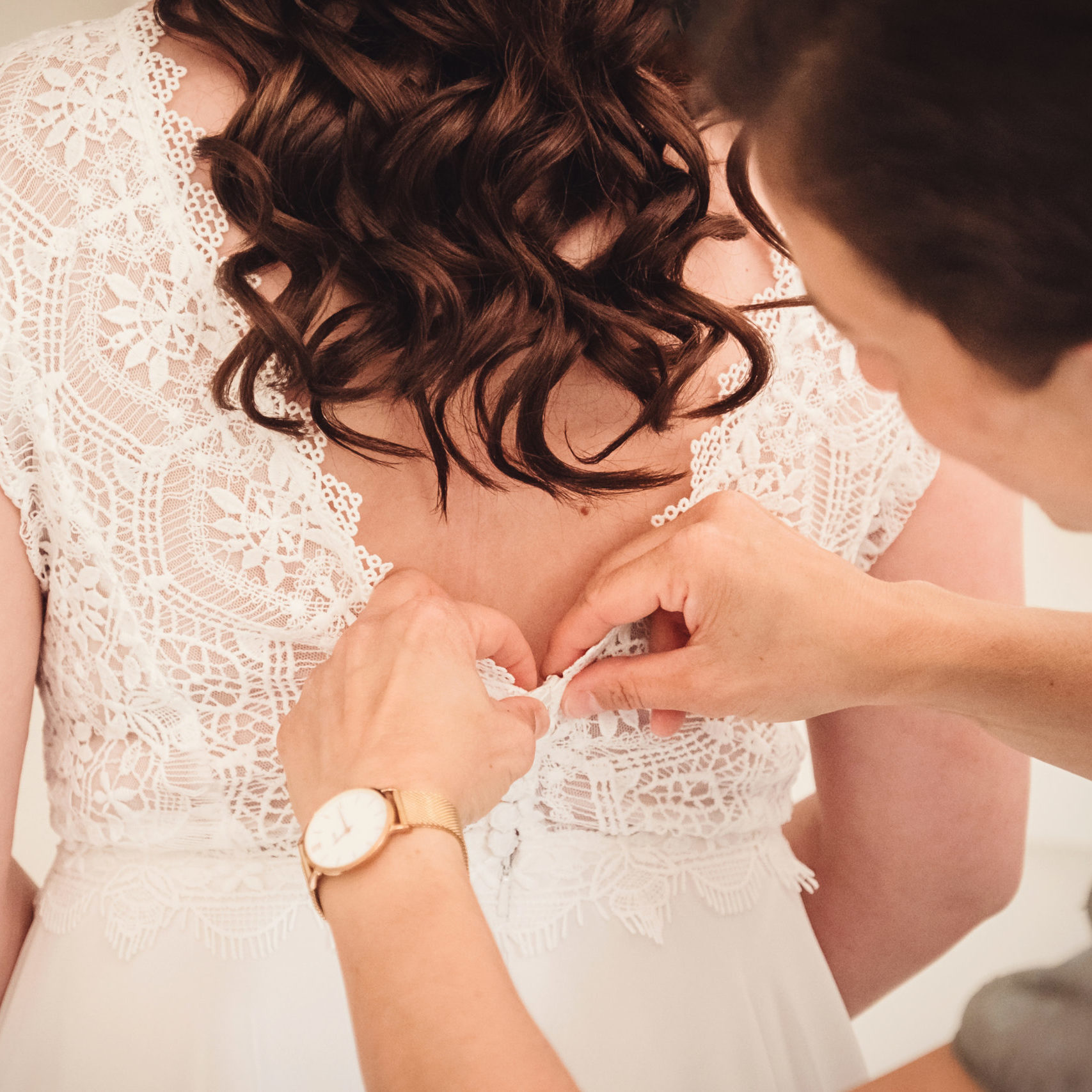 Weddingplannrin knöpft das Brautkleid zu